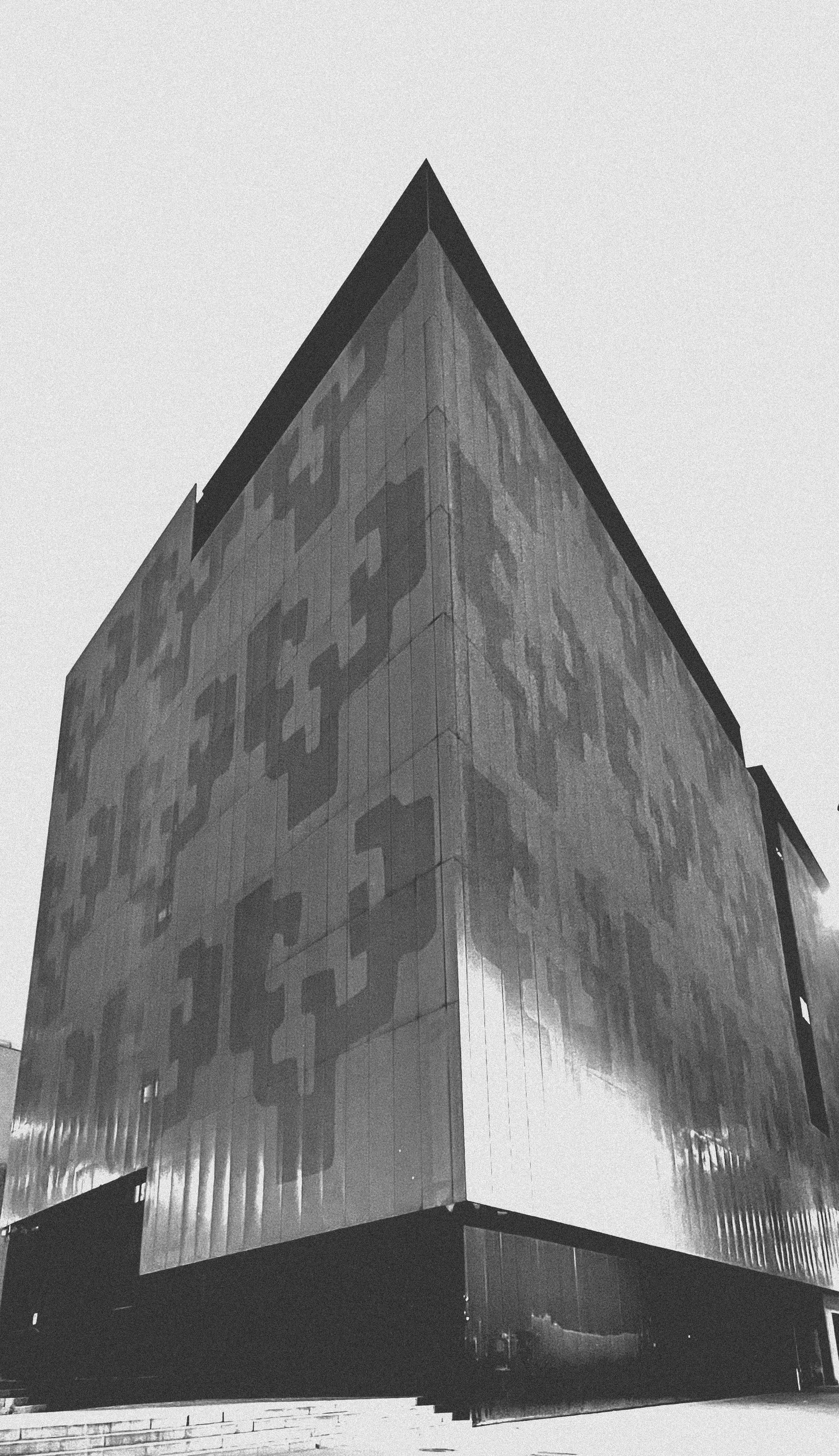 Edificio de fachada metálica con dibujos geométricos, visto desde abajo